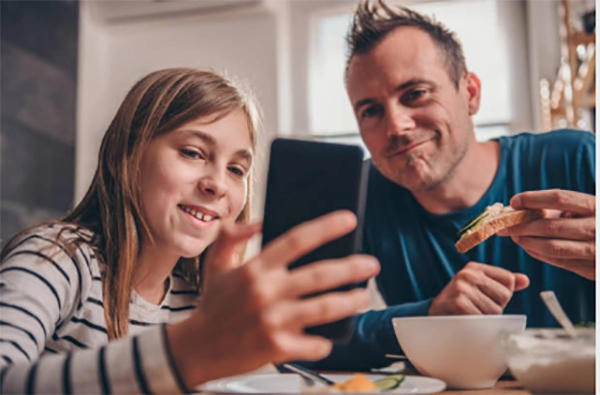 Parent and teenager looking at a phone screen together at a kitchen table